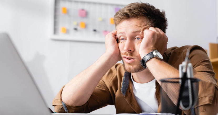 Müder Mann sitzt im Büro am Schreibtisch.